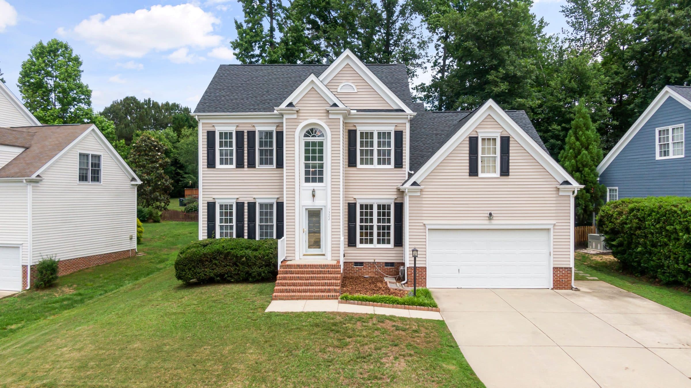 Two-story home with vinyl siding, black shutters and a two-car garage