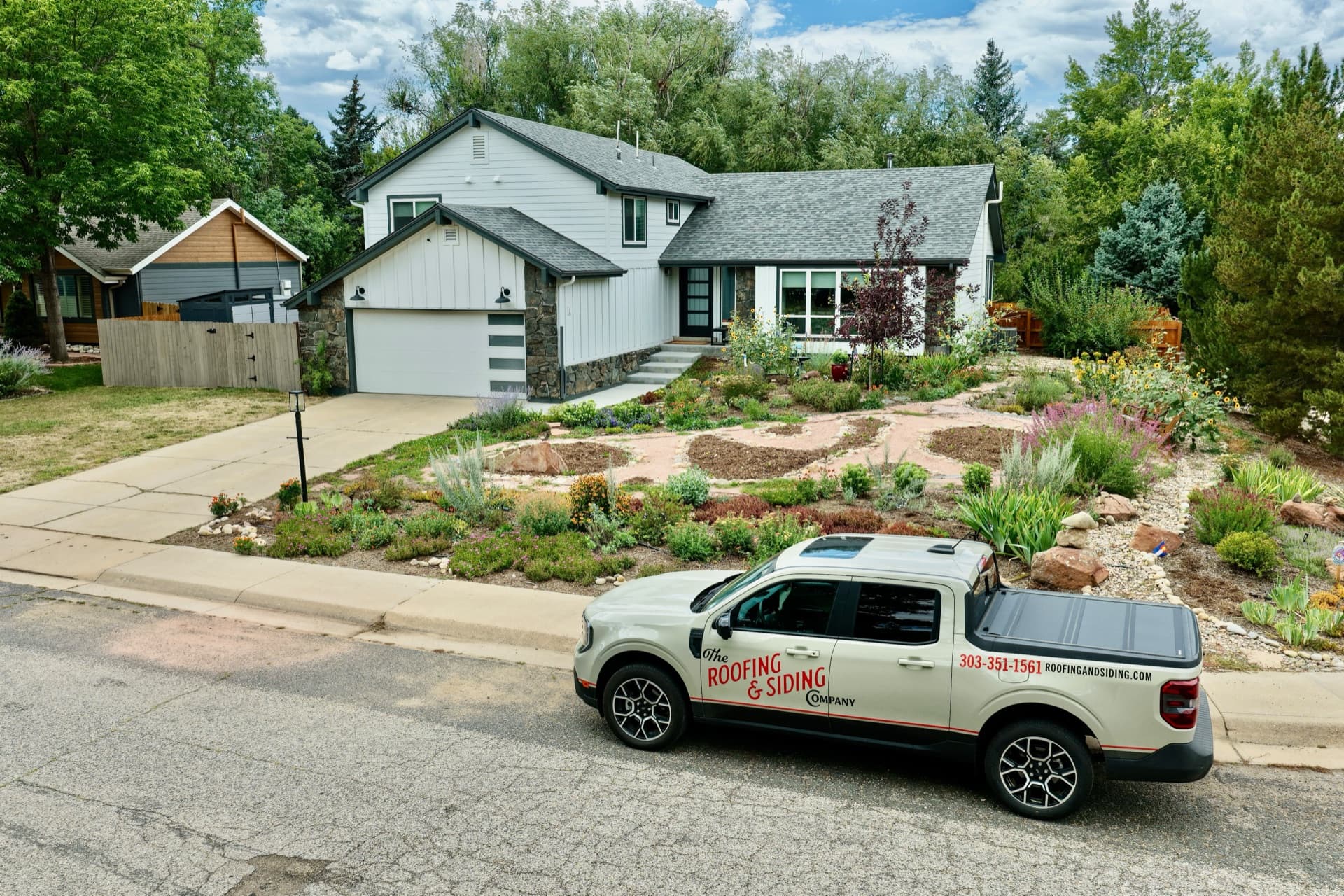 Aerial view of completed James Hardie siding installation on a home in Boulder, CO, with The Roofing & Siding Company truck parked in front