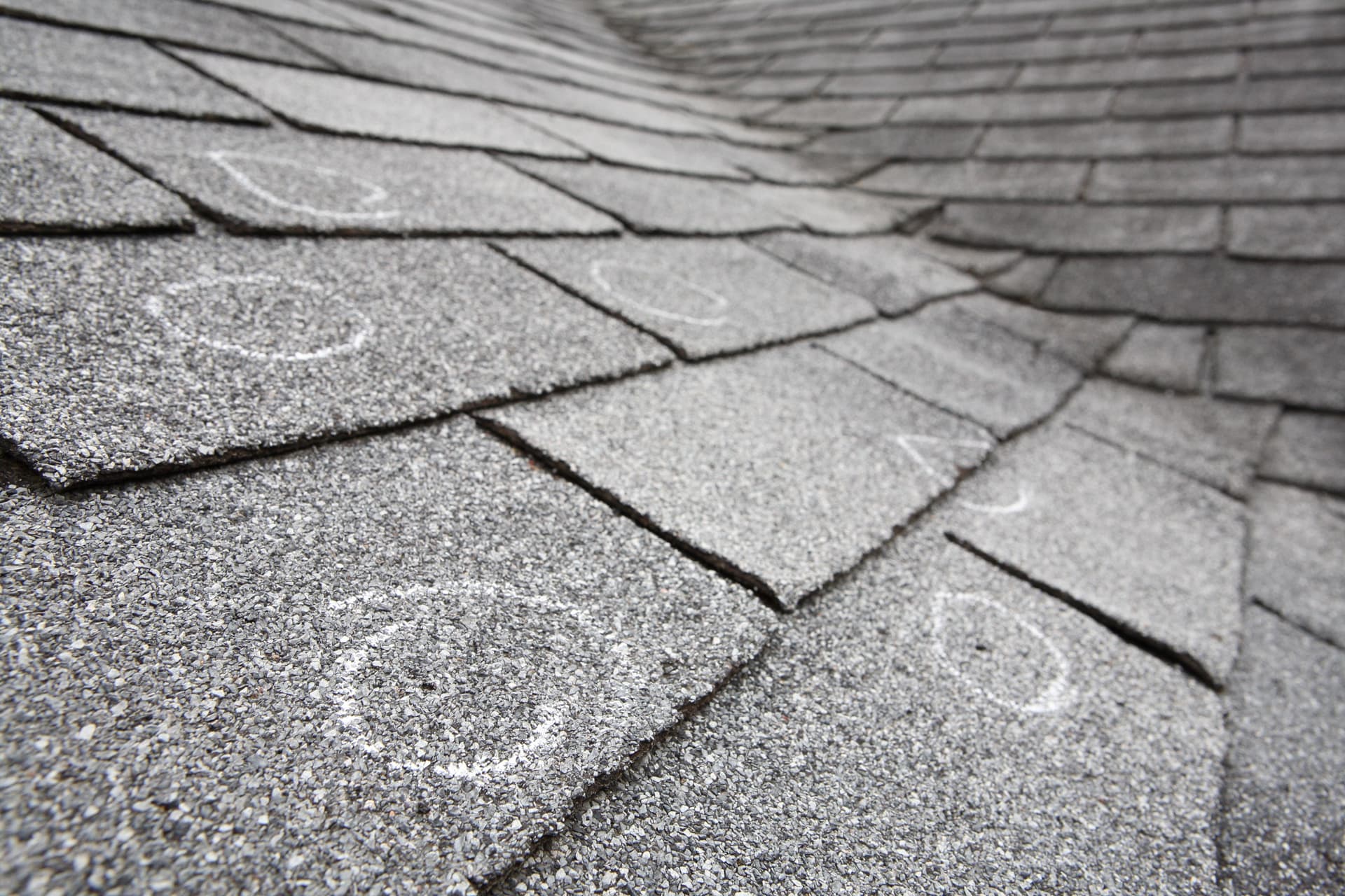 Chalk-marked hail damage on asphalt shingle roof during inspection in Denver Colorado