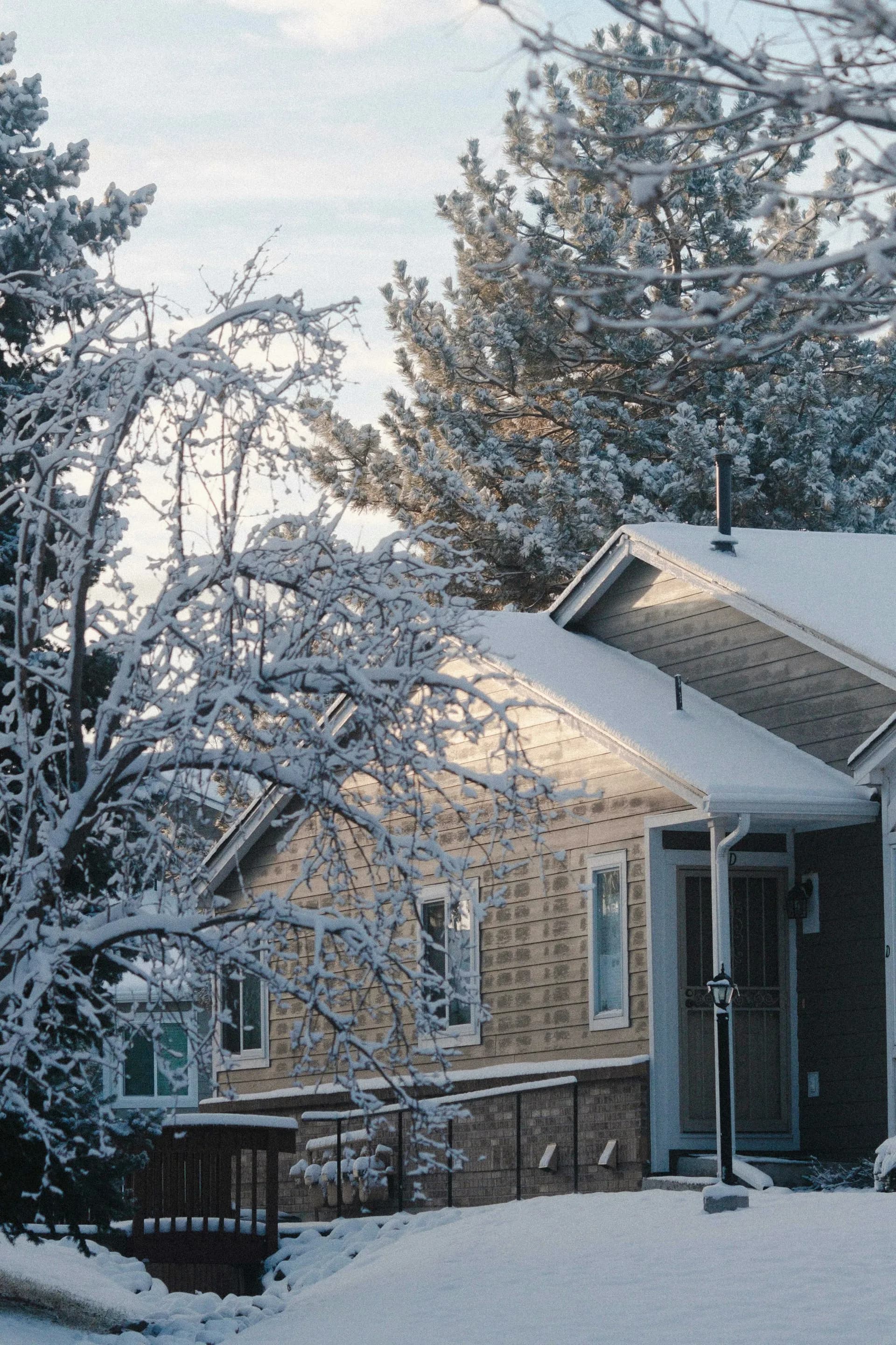 Snow-covered residential home with visible roof and siding in Thornton Colorado