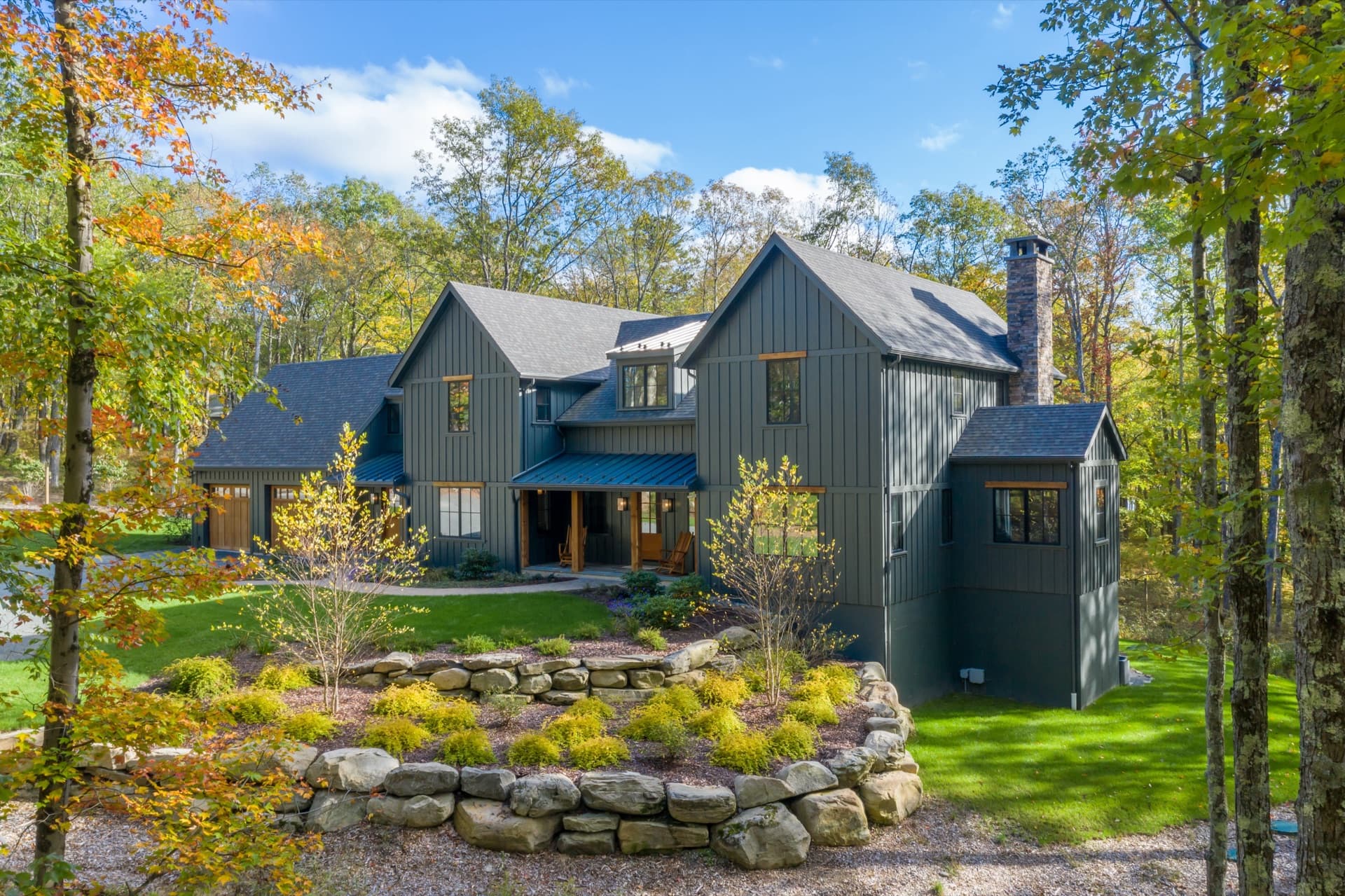 Large home with dark board-and-batten siding surrounded by fall foliage in Colorado