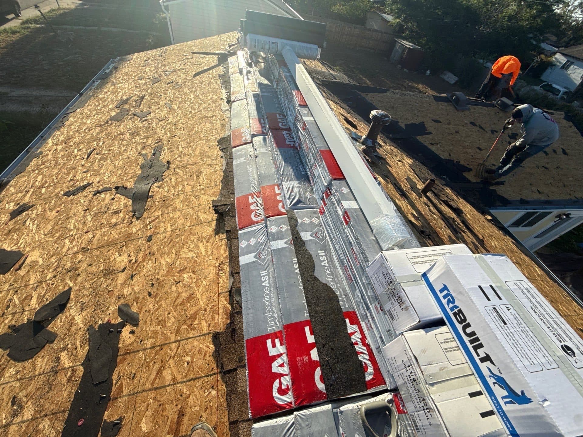 Progress picture of a roof replacement in Commerce City, Colorado. Bundles of shingles are on the roof and the original roof has been torn off.