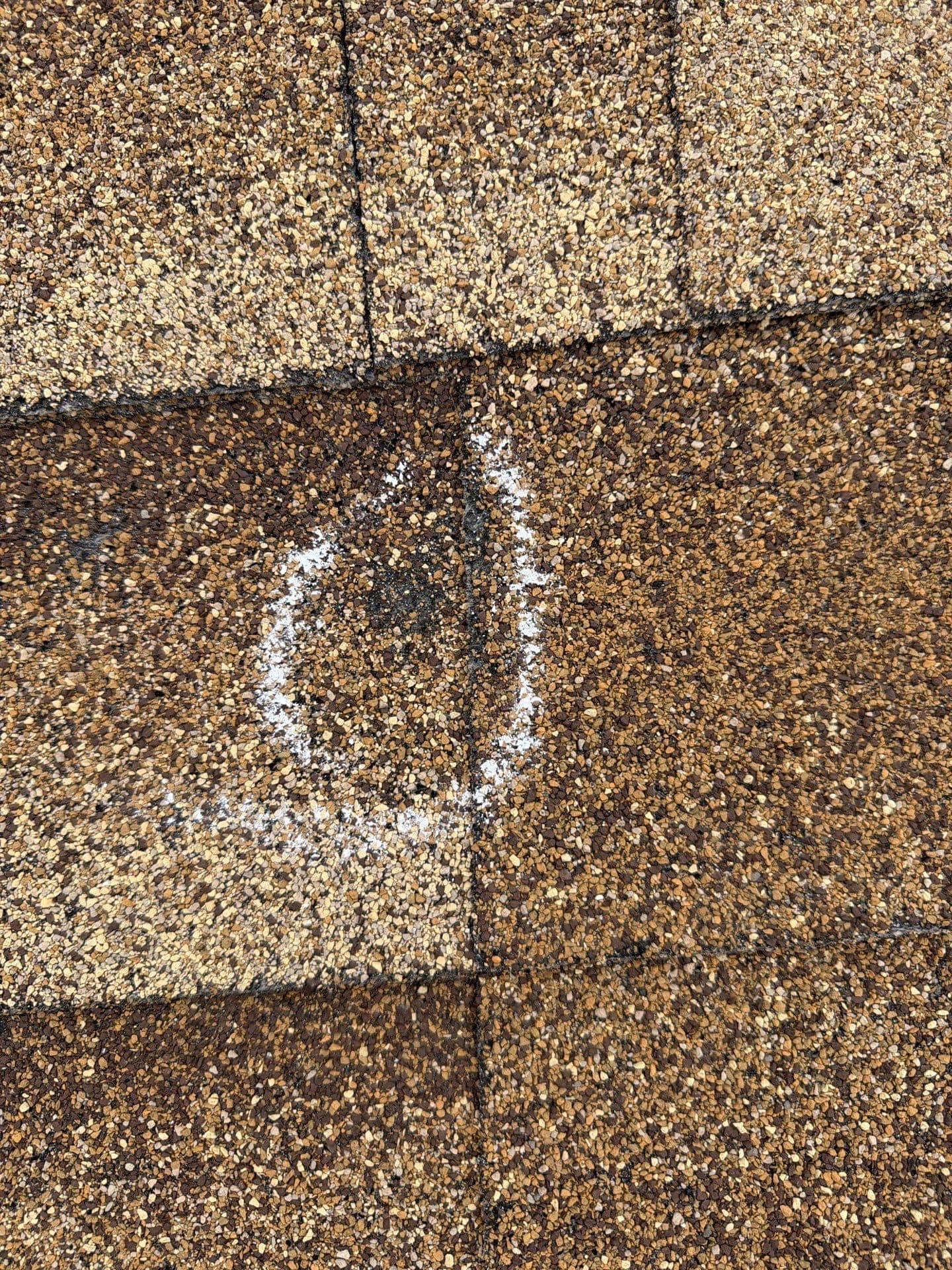 A close up of hail damage marked with white chalk on a roof in Commerce City, Colorado.