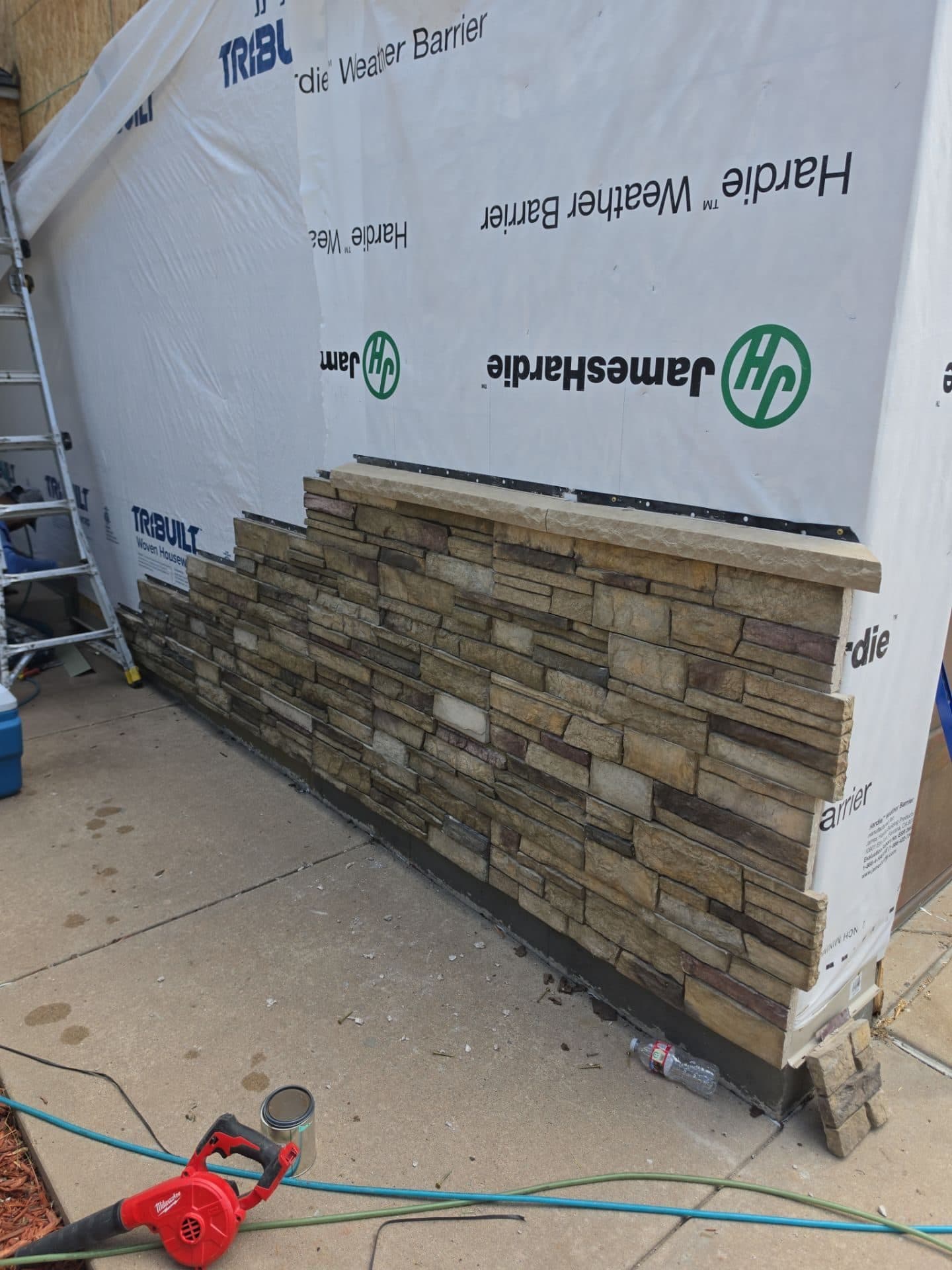 Installing Versetta Stone veneer accent along the base of the exterior in Aurora, CO.