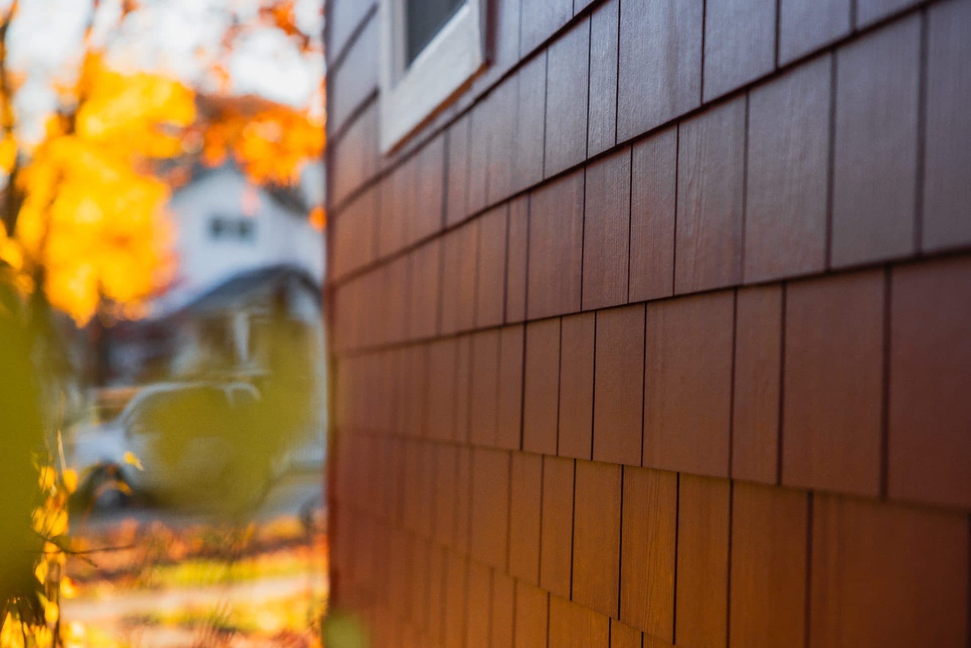 James Hardie shake siding with fall foliage in the background.