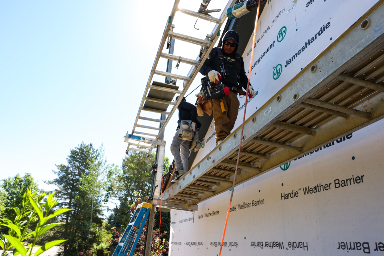 Crew member on scaffold installing James Hardie weather barrier and siding on a Boulder, CO home