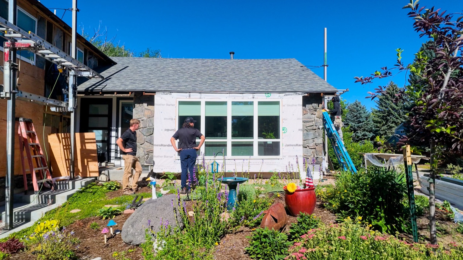 Two Roofing & Siding Company crew members reviewing siding installation progress on the rear of a Boulder, CO home